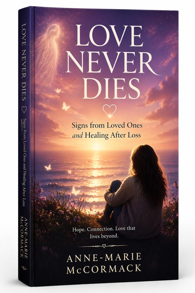 Love Never Dies: Signs from Loved Ones and Healing After Loss by Anne-Marie McCormack, showing a woman sitting by the ocean at sunset with a glowing spiritual presence above, symbolising connection after loss.